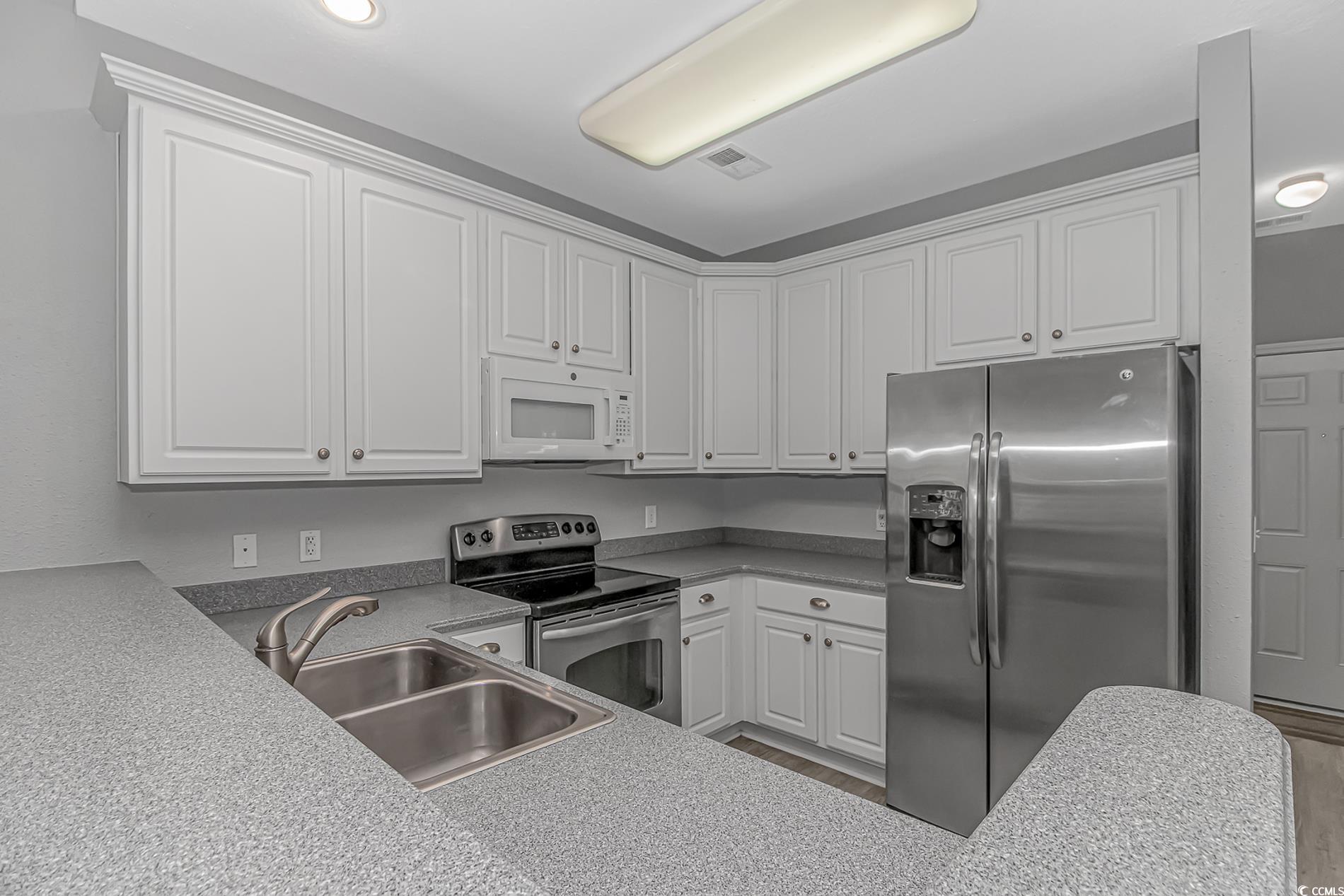 751 Painted Bunting Drive, Unit E Murrells Inlet, SC 29576 - Photo 13 of 40 Kitchen with appliances with stainless steel finishes, a sink, white cabinetry, and wood finished floors