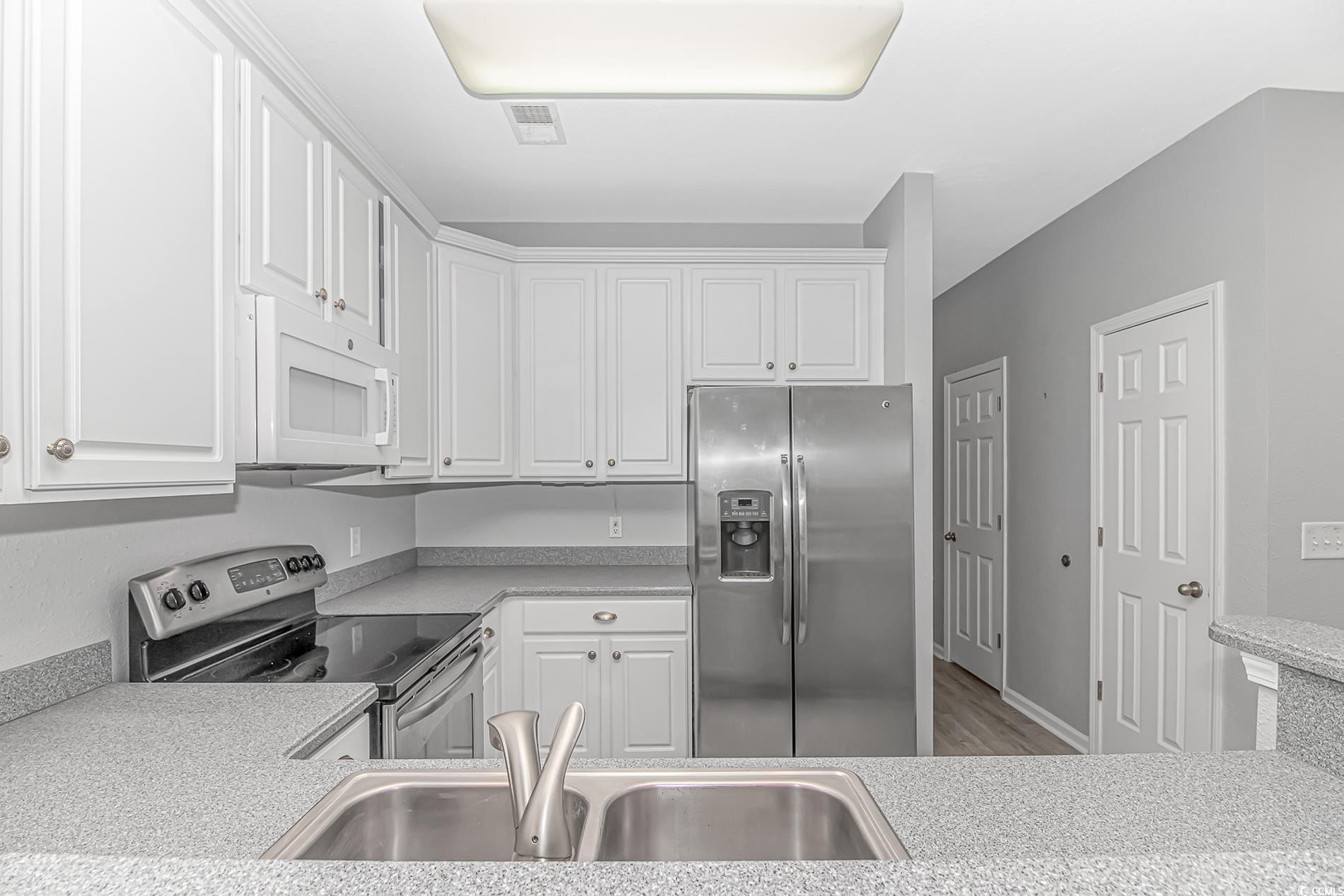 751 Painted Bunting Drive, Unit E Murrells Inlet, SC 29576 - Photo 14 of 40 Kitchen with stainless steel appliances, a sink, light countertops, and white cabinetry