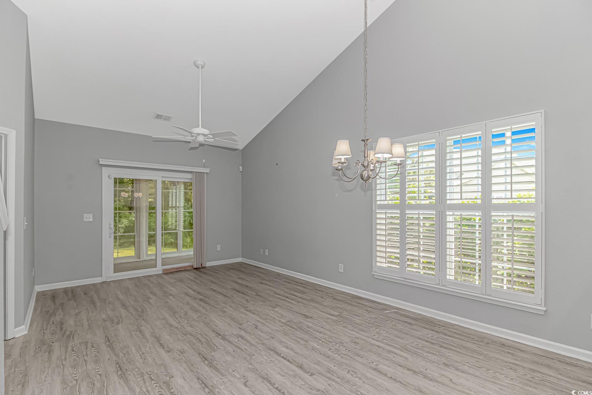 751 Painted Bunting Drive, Unit E Murrells Inlet, SC 29576 - Photo 16 of 40 Empty room with ceiling fan, wood finished floors, high vaulted ceiling, a chandelier, and baseboards