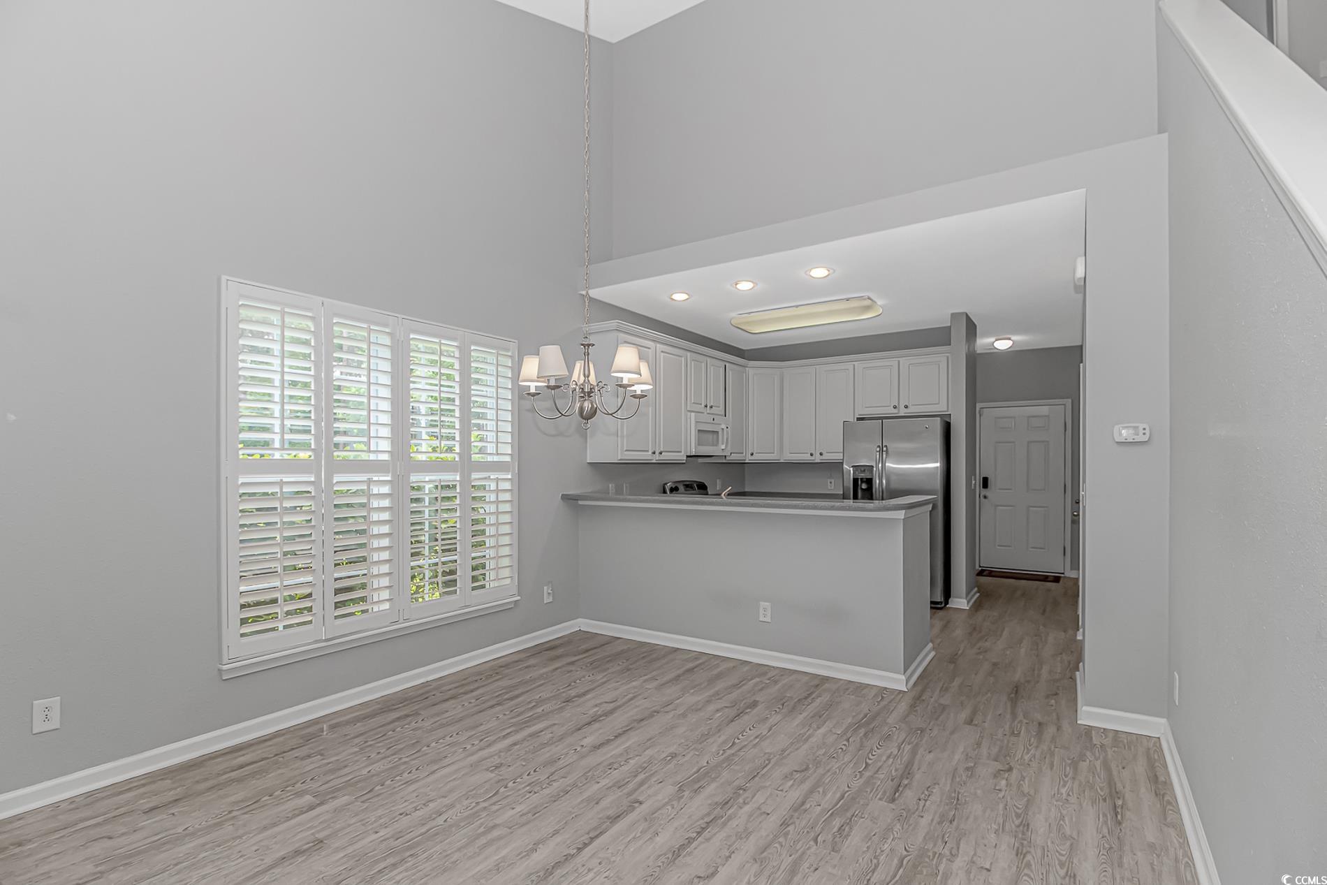 751 Painted Bunting Drive, Unit E Murrells Inlet, SC 29576 - Photo 18 of 40 Kitchen with white microwave, a chandelier, baseboards, light wood-style floors, and a high ceiling