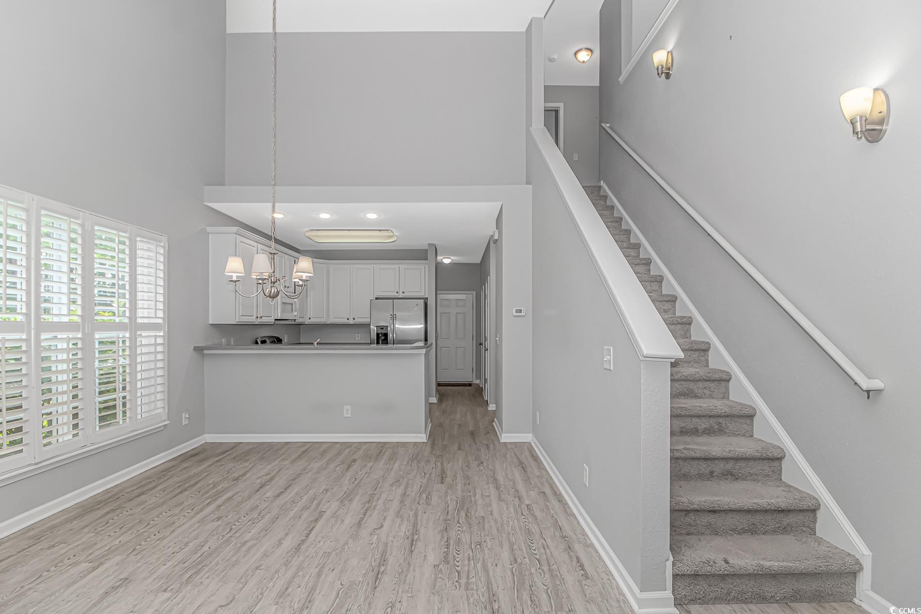 751 Painted Bunting Drive, Unit E Murrells Inlet, SC 29576 - Photo 19 of 40 Kitchen with stainless steel fridge, light wood finished floors, a chandelier, a high ceiling, and hanging light fixtures
