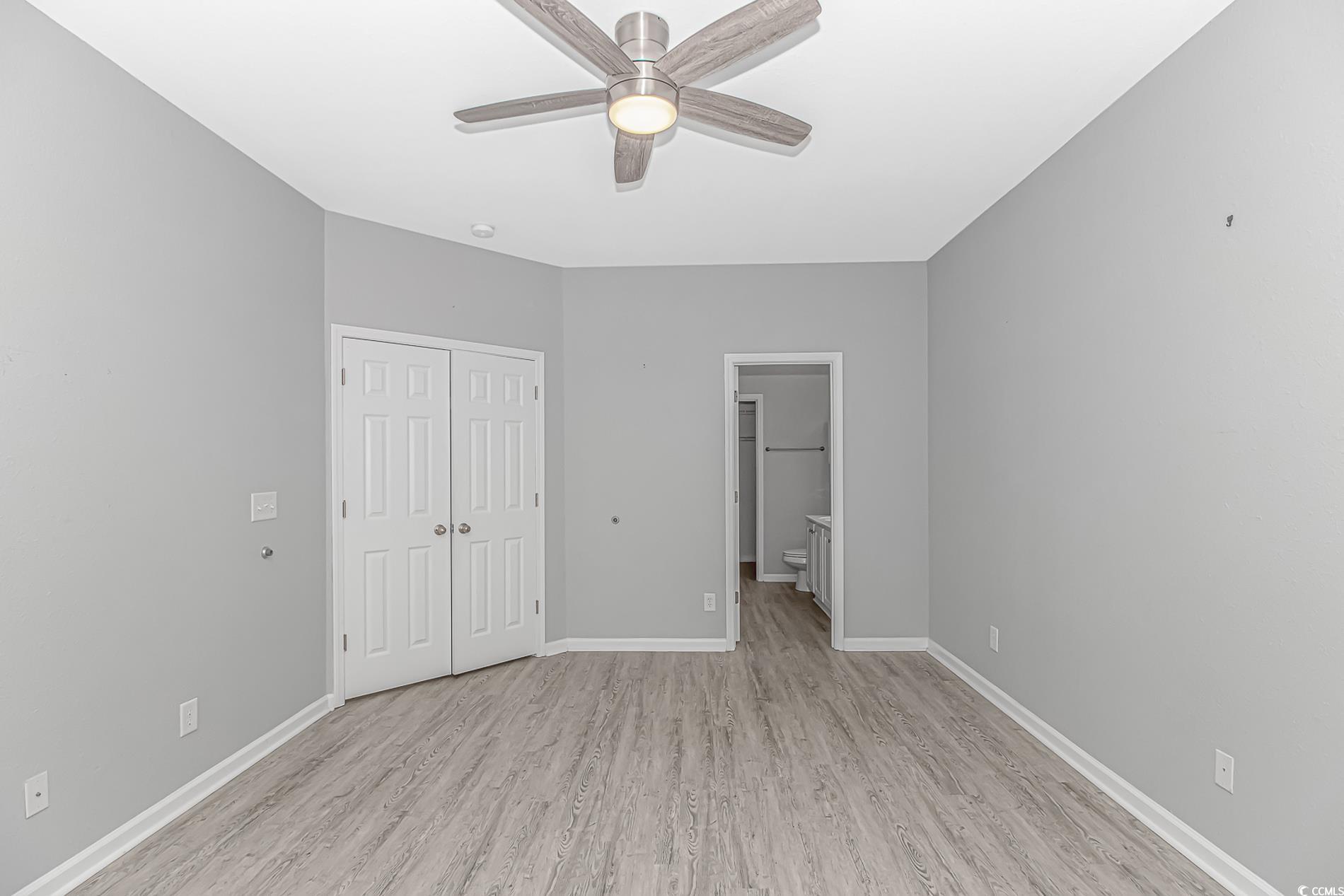 751 Painted Bunting Drive, Unit E Murrells Inlet, SC 29576 - Photo 21 of 40 Unfurnished bedroom featuring light wood-style floors, a closet, baseboards, ensuite bathroom, and a ceiling fan
