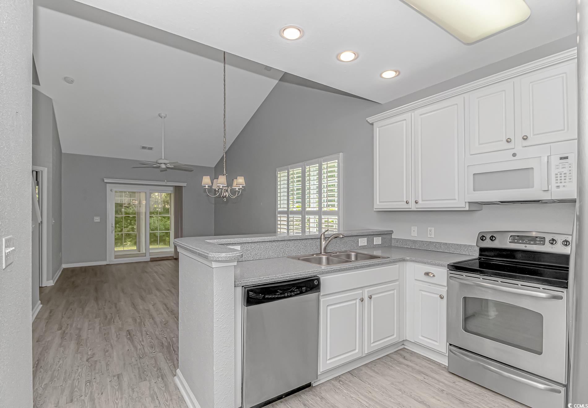 751 Painted Bunting Drive, Unit E Murrells Inlet, SC 29576 - Photo 9 of 40 Kitchen featuring stainless steel appliances, lofted ceiling, a sink, light wood-style flooring, and a peninsula