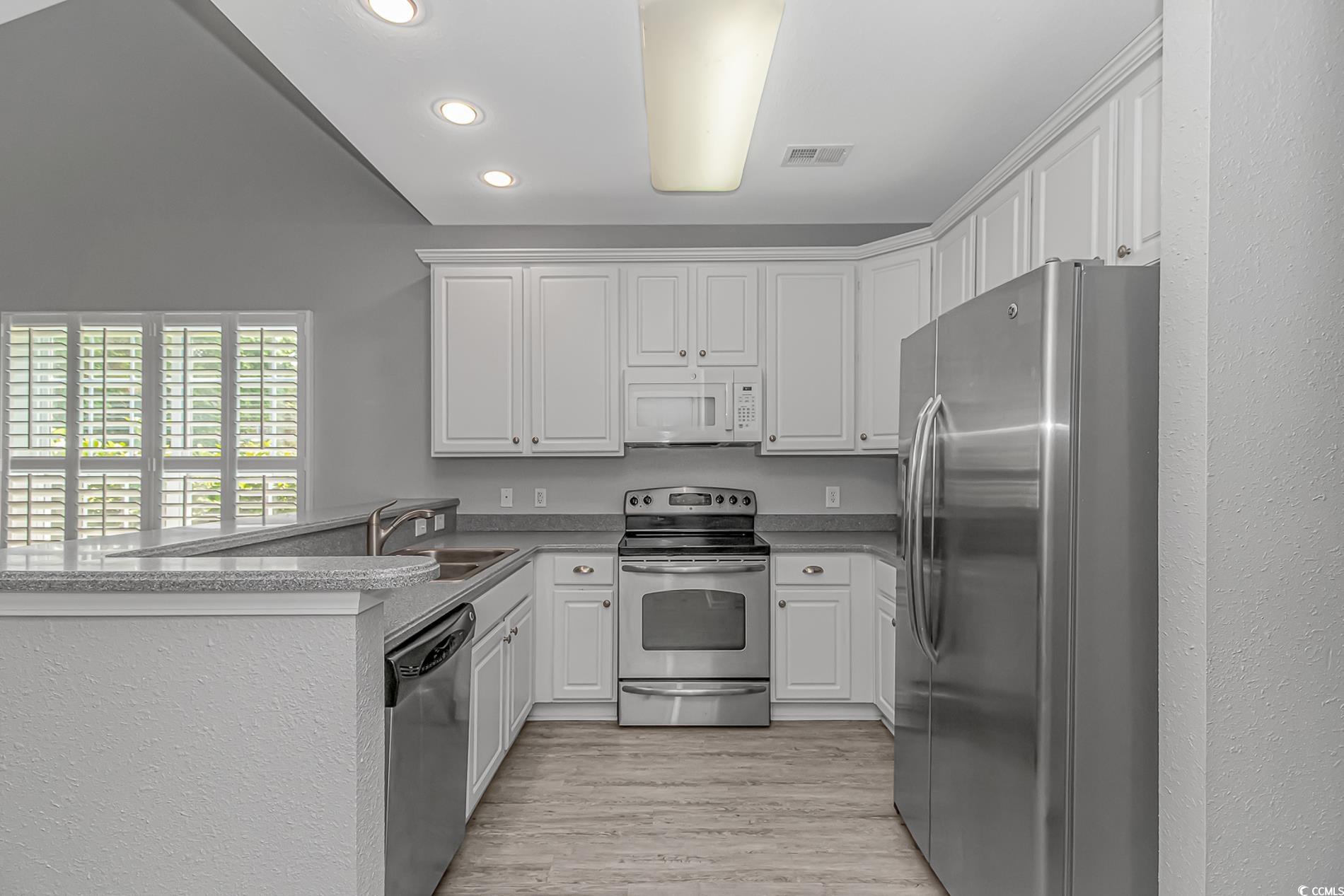 751 Painted Bunting Drive, Unit E Murrells Inlet, SC 29576 - Photo 10 of 40 Kitchen featuring appliances with stainless steel finishes, a sink, recessed lighting, white cabinets, and a peninsula