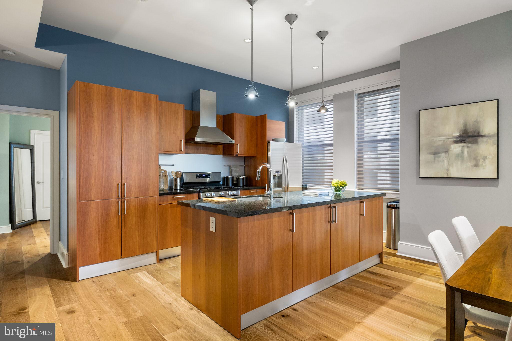1515 Locust Street, Unit 401 Philadelphia, PA 19102 - Photo 4 of 35 a kitchen with stainless steel appliances granite countertop wooden floors a stove a sink and a refrigerator