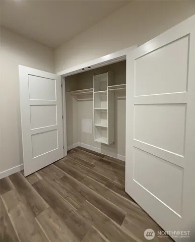 a view of an empty room with wooden floor and closet