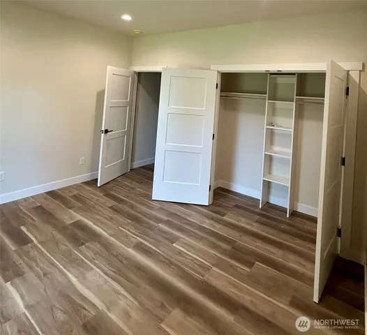 a view of an empty room with wooden floor and closet