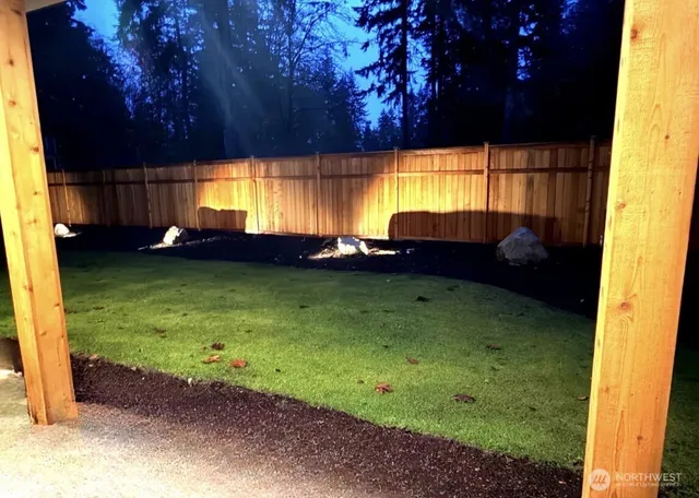 a view of a backyard with couches plants and large trees