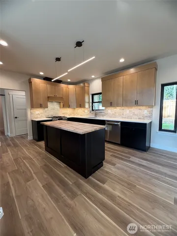 a large kitchen with kitchen island a sink dishwasher a stove and a refrigerator with wooden floor