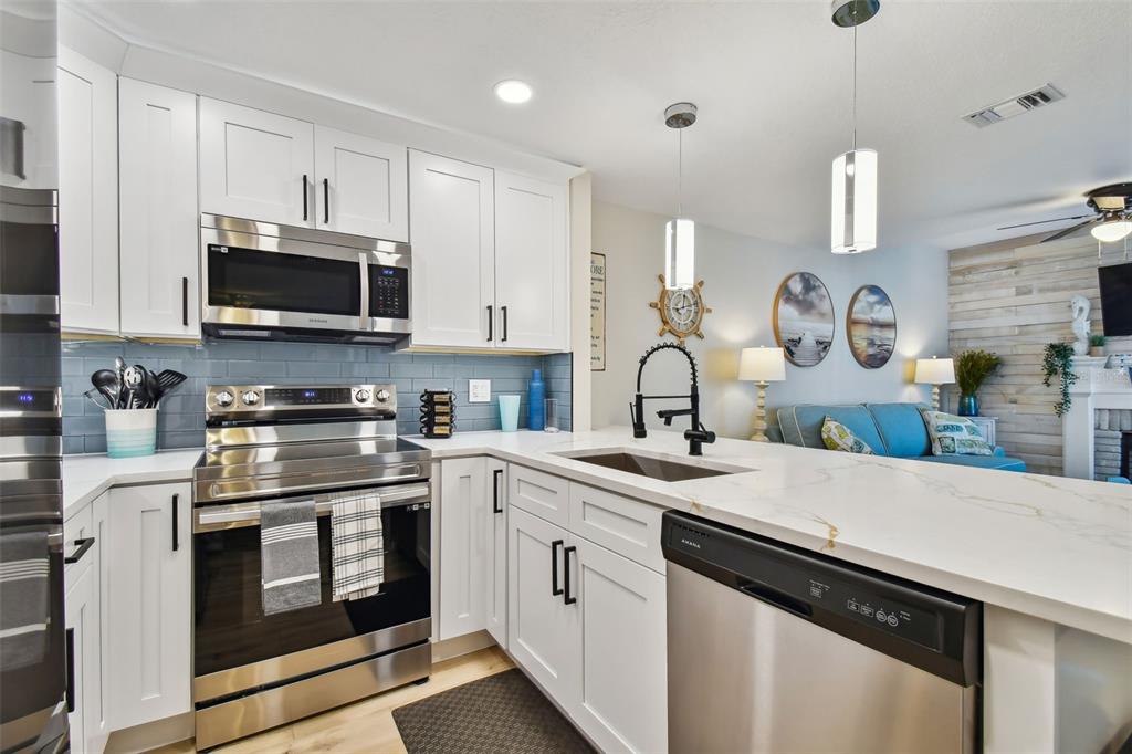315 Medallion Boulevard, Unit E Madeira Beach, FL 33708 - Photo 14 of 78 a kitchen with granite countertop a sink stainless steel appliances and cabinets