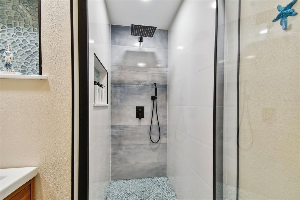 315 Medallion Boulevard, Unit E Madeira Beach, FL 33708 - Photo 27 of 78 a bathroom with a glass shower door