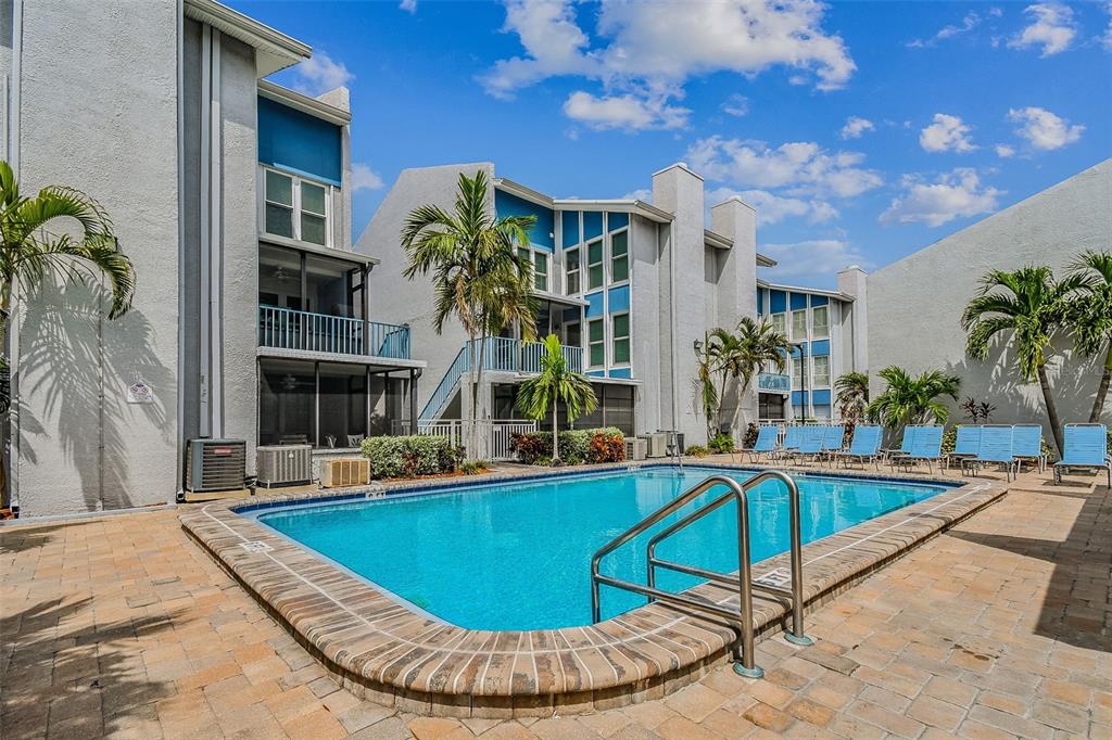 315 Medallion Boulevard, Unit E Madeira Beach, FL 33708 - Photo 55 of 78 a view of a swimming pool with chairs
