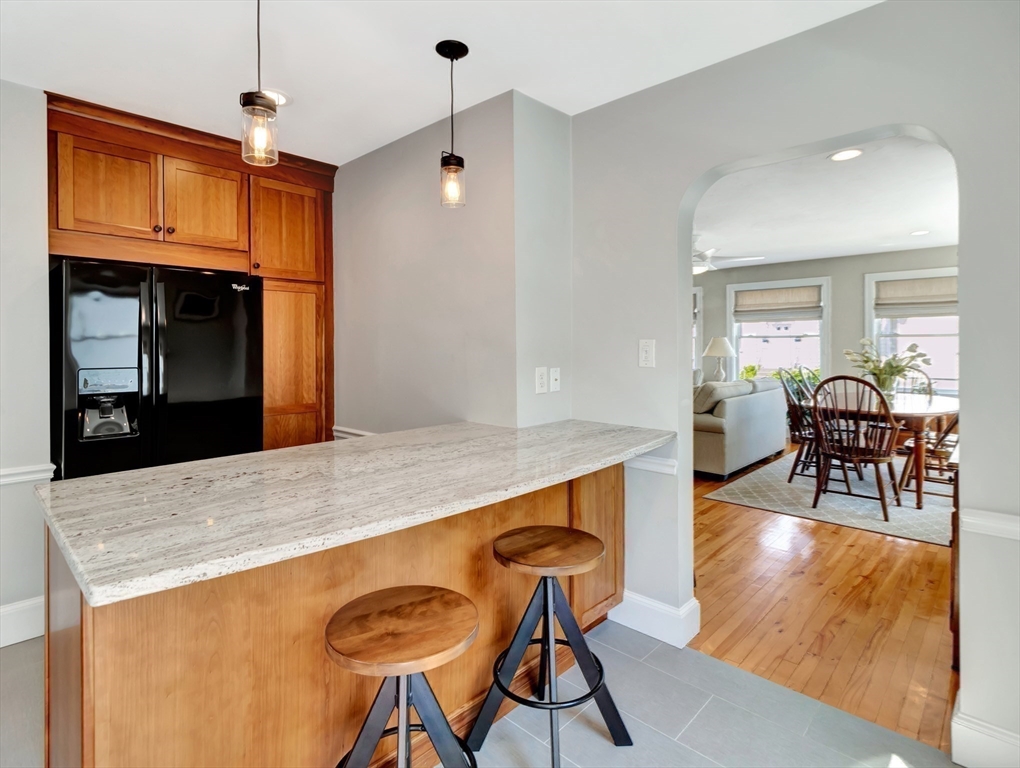 26 C Street Hull, MA 02045 - Photo 19 of 42 a kitchen with stainless steel appliances granite countertop a stove a refrigerator a microwave a dining table and chairs with wooden floor