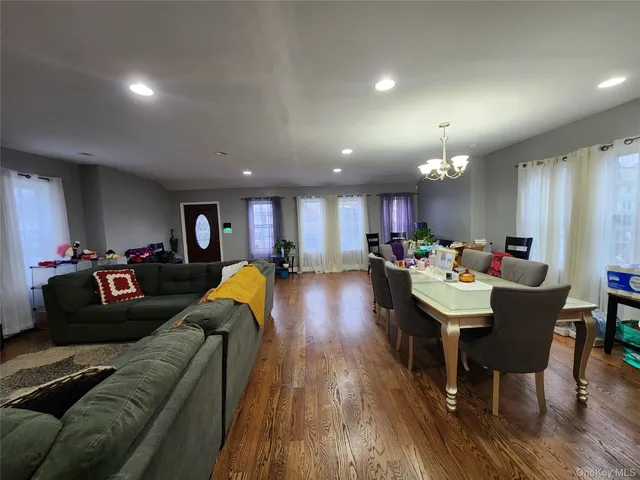 a living room with furniture kitchen view and a wooden floor