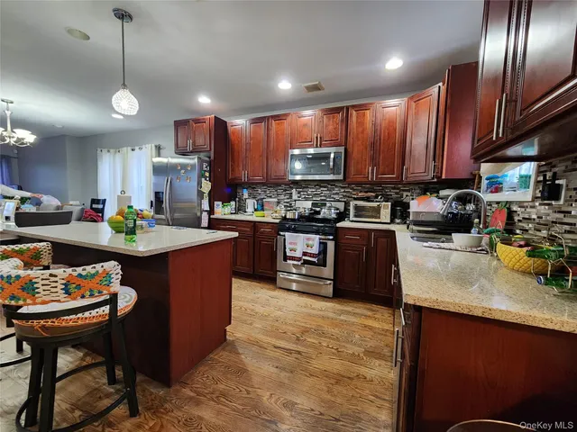 a kitchen with stainless steel appliances granite countertop a stove a sink a microwave a center island and chairs