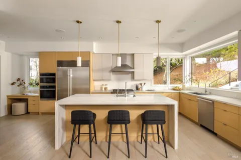 a kitchen with stainless steel appliances kitchen island granite countertop a dining table chairs and white cabinets