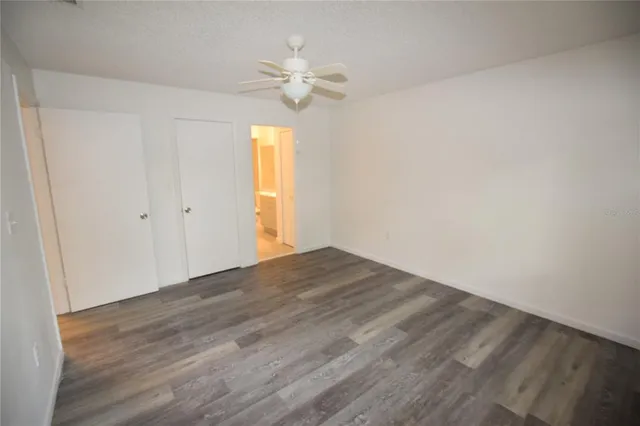 a view of empty room with wooden floor and fan
