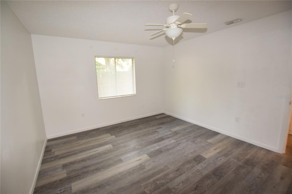 904 Sumter Street Leesburg, FL 34748 - Photo 16 of 27 an empty room with wooden floor fan and windows