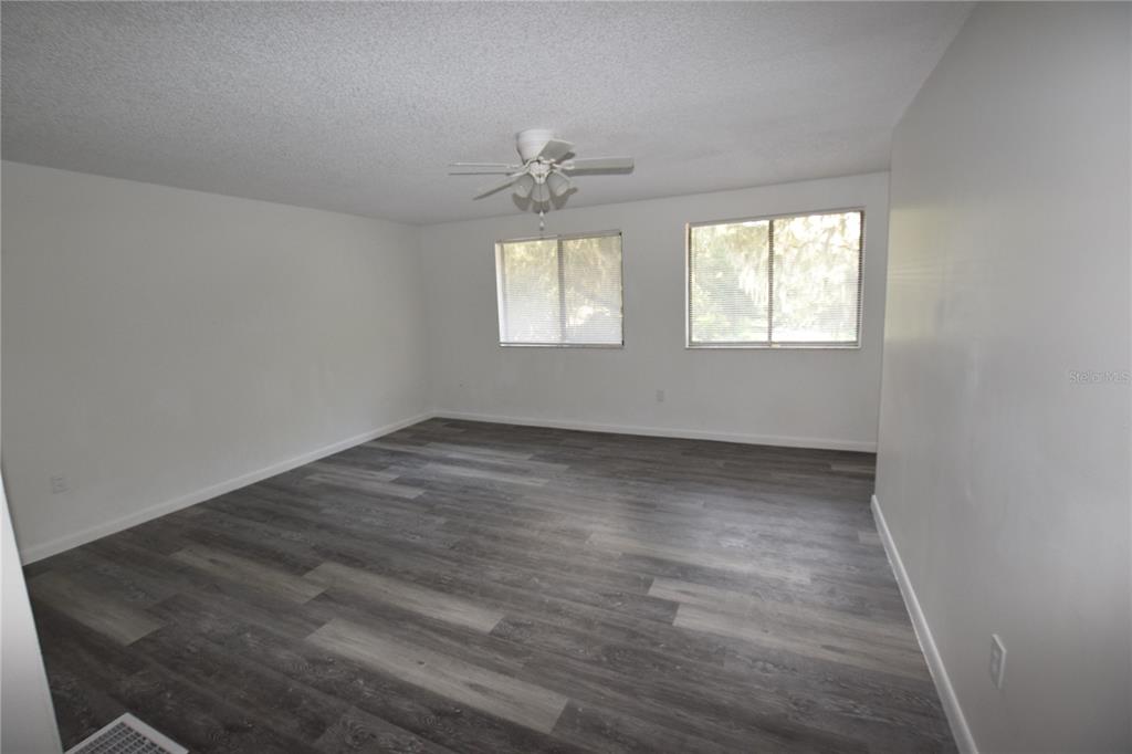 904 Sumter Street Leesburg, FL 34748 - Photo 18 of 27 an empty room with wooden floor ceiling fan and windows