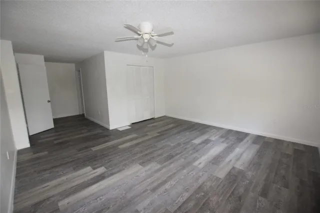 an empty room with wooden floor and fan