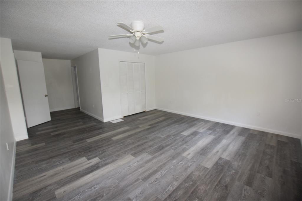 904 Sumter Street Leesburg, FL 34748 - Photo 19 of 27 an empty room with wooden floor and fan