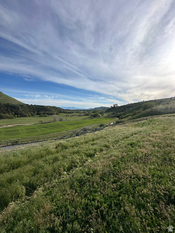 4250 East Cub River Road Preston, ID 83263 - Photo 6 of 18 Expansive natural landscape featuring rolling green hills, a winding stream, and distant mountain ranges under a vast sky