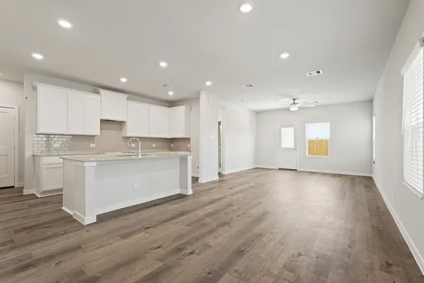 a view of kitchen with granite countertop refrigerator oven sink and white cabinets with wooden floor