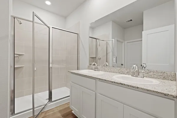 a bathroom with a granite countertop sink a mirror a vanity and a shower