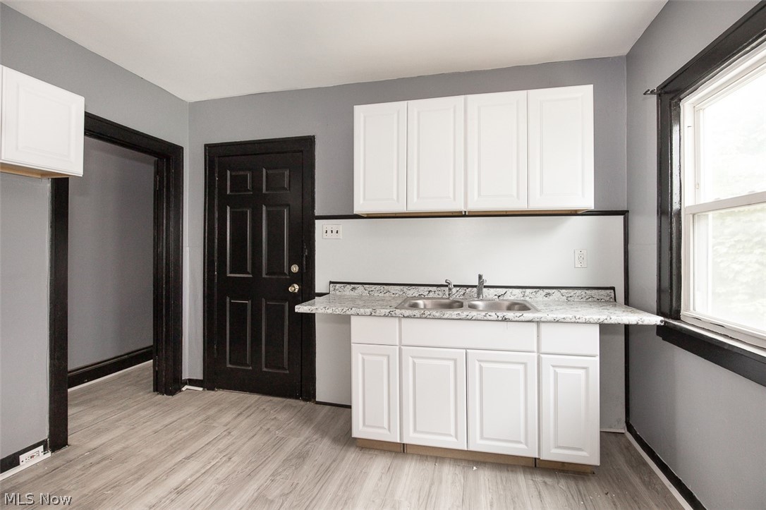 1868-1870 Lampson Road Cleveland, OH 44112 - Photo 25 of 36 Kitchen area featuring bright white cabinetry, wood-finish flooring, a double basin sink, and a speckled countertop