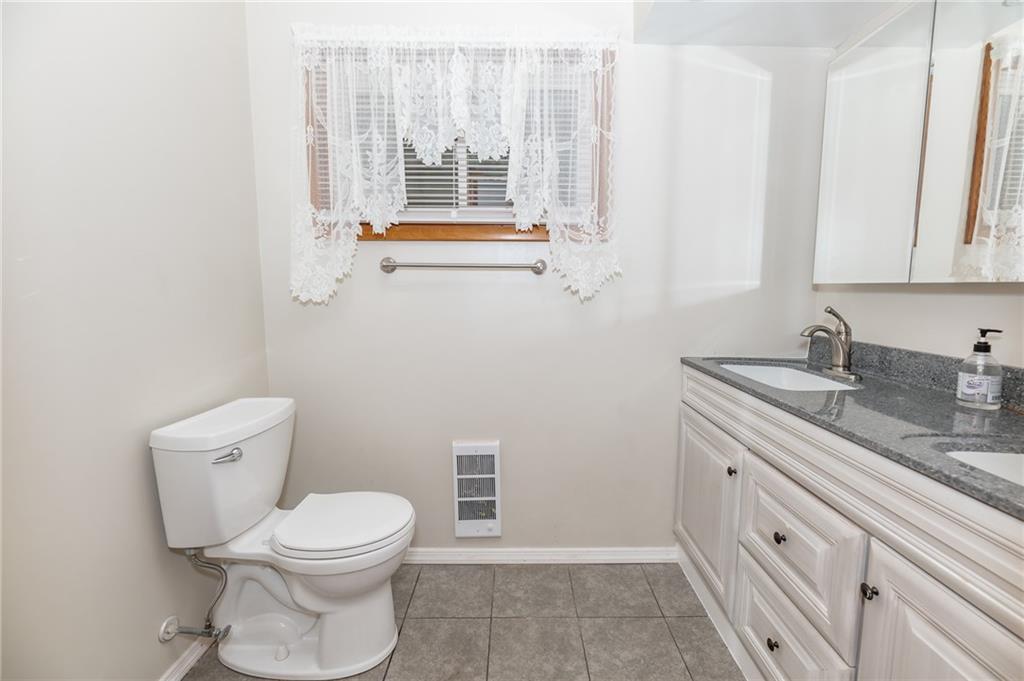 225 Courtland Road Indiana, PA 15701 - Photo 21 of 38 a bathroom with a granite countertop toilet a sink a mirror and a window