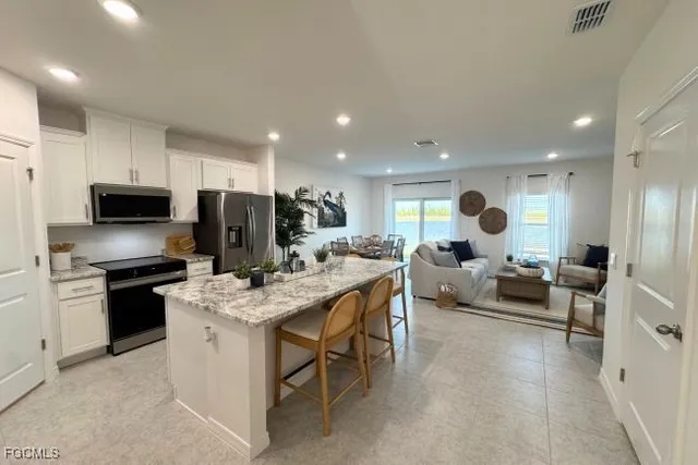 a kitchen with stainless steel appliances granite countertop a stove top oven a dining table and chairs with wooden floor