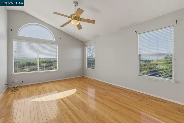a view of empty room with wooden floor and fan