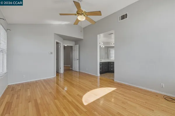 a view of empty room with wooden floor and fan