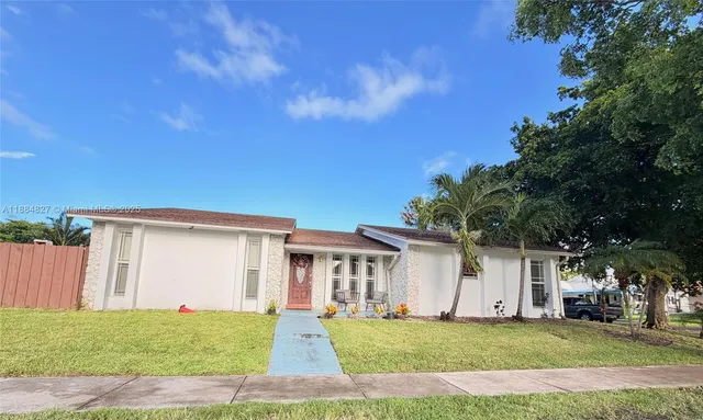 a white house with a big yard and large trees