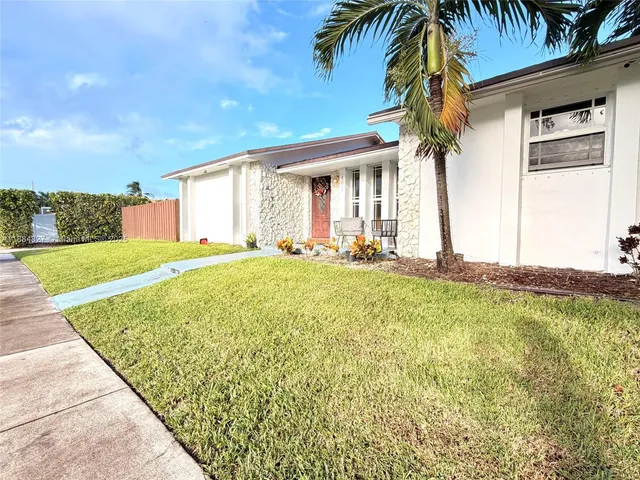a view of a house with a yard and palm trees