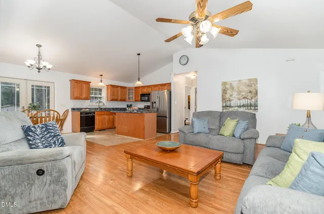 a living room with furniture kitchen view and a chandelier