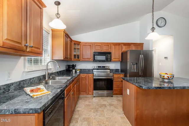a kitchen with stainless steel appliances granite countertop a sink a stove and a refrigerator