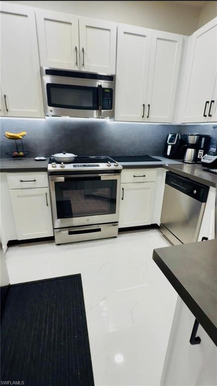 14122 Southwest 276th Street Homestead, FL 33032 - Photo 21 of 47 Kitchen with dark countertops, stainless steel appliances, white cabinets, and light marble finish floors