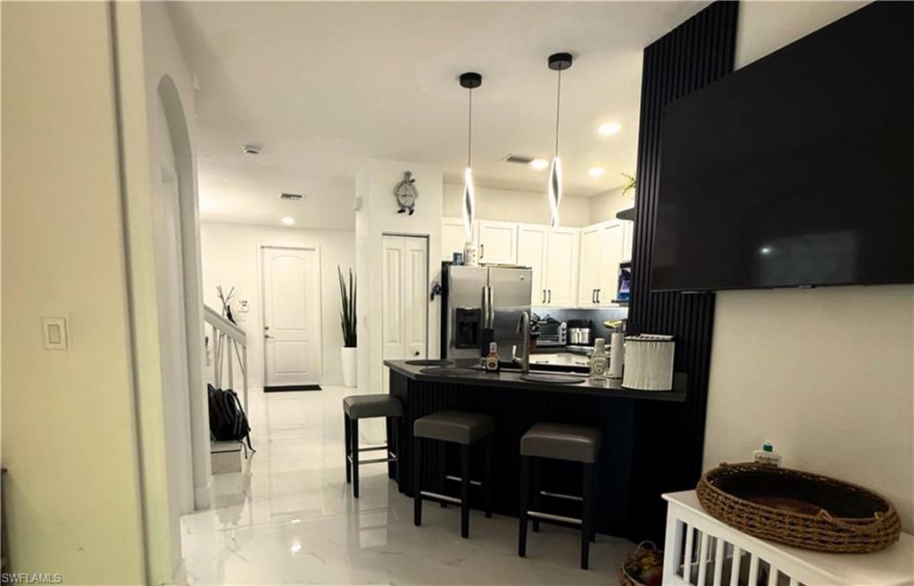14122 Southwest 276th Street Homestead, FL 33032 - Photo 5 of 47 Kitchen with dark countertops, a peninsula, stainless steel fridge with ice dispenser, a breakfast bar, and light marble finish floors