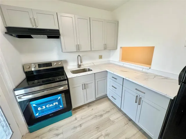a kitchen with appliances cabinets and a wooden floor