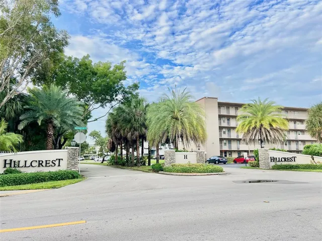a view of sign board with buildings and trees in the background