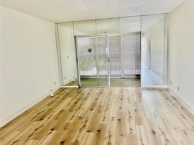 a view of an empty room with wooden floor and a bathroom