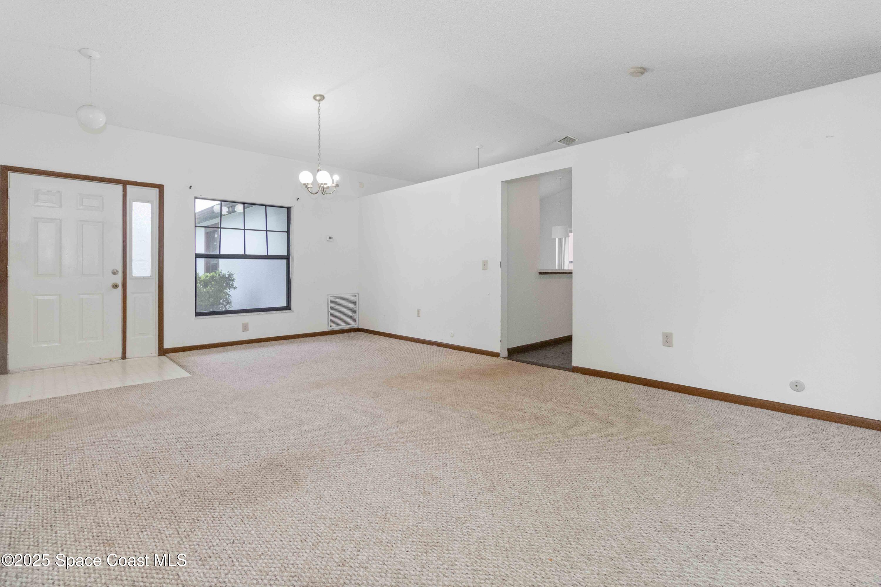 1873 Longleaf Road Cocoa, FL 32926 - Photo 3 of 30 an empty room with chandelier and windows