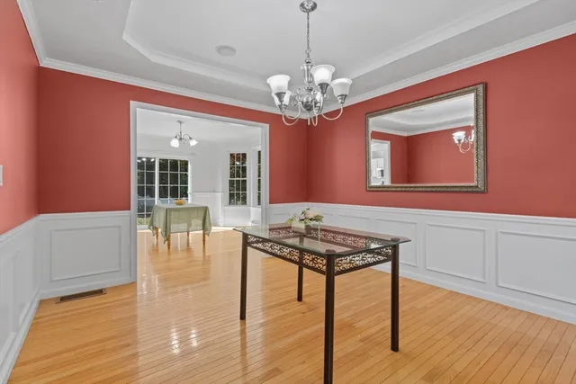 a dining room with wooden floor a chandelier a wooden table and chairs