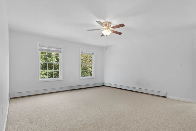 an empty room with windows and fan