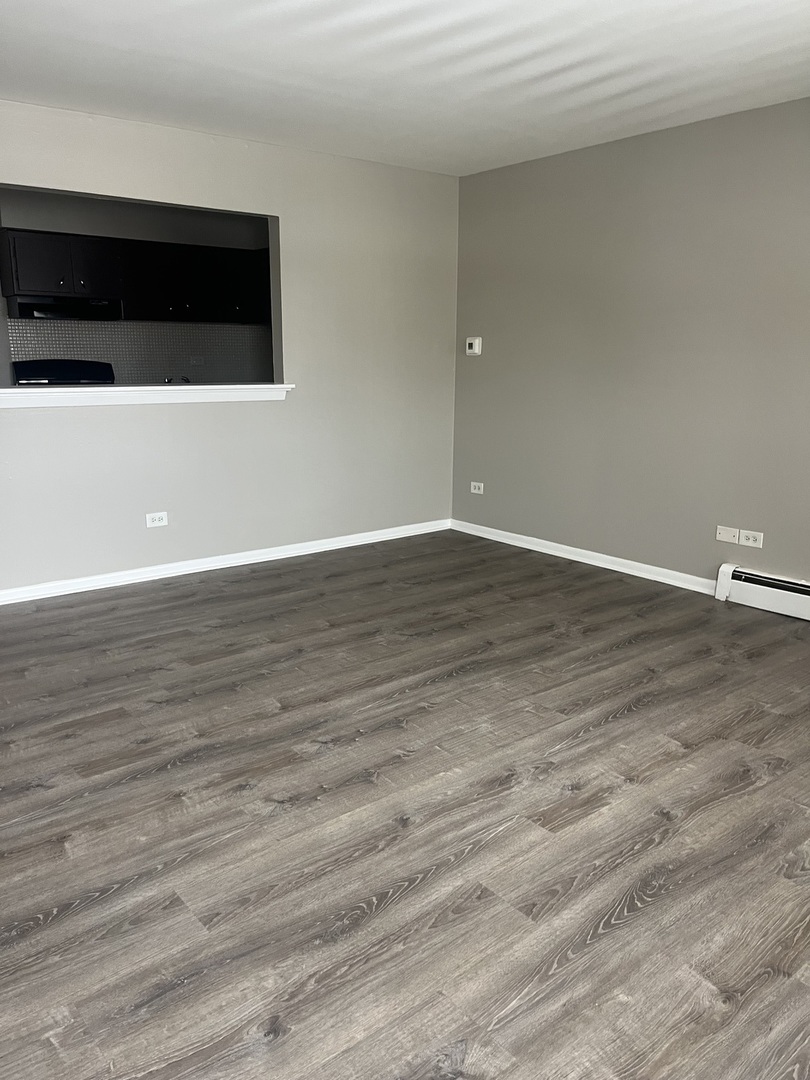 8817 South Roberts Road, Unit 7 Hickory Hills, IL 60457 - Photo 2 of 9 a view of an empty room with wooden floor and a window