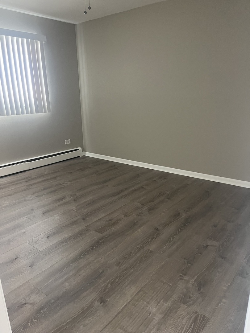 8817 South Roberts Road, Unit 7 Hickory Hills, IL 60457 - Photo 9 of 9 a view of an empty room with wooden floor and a window