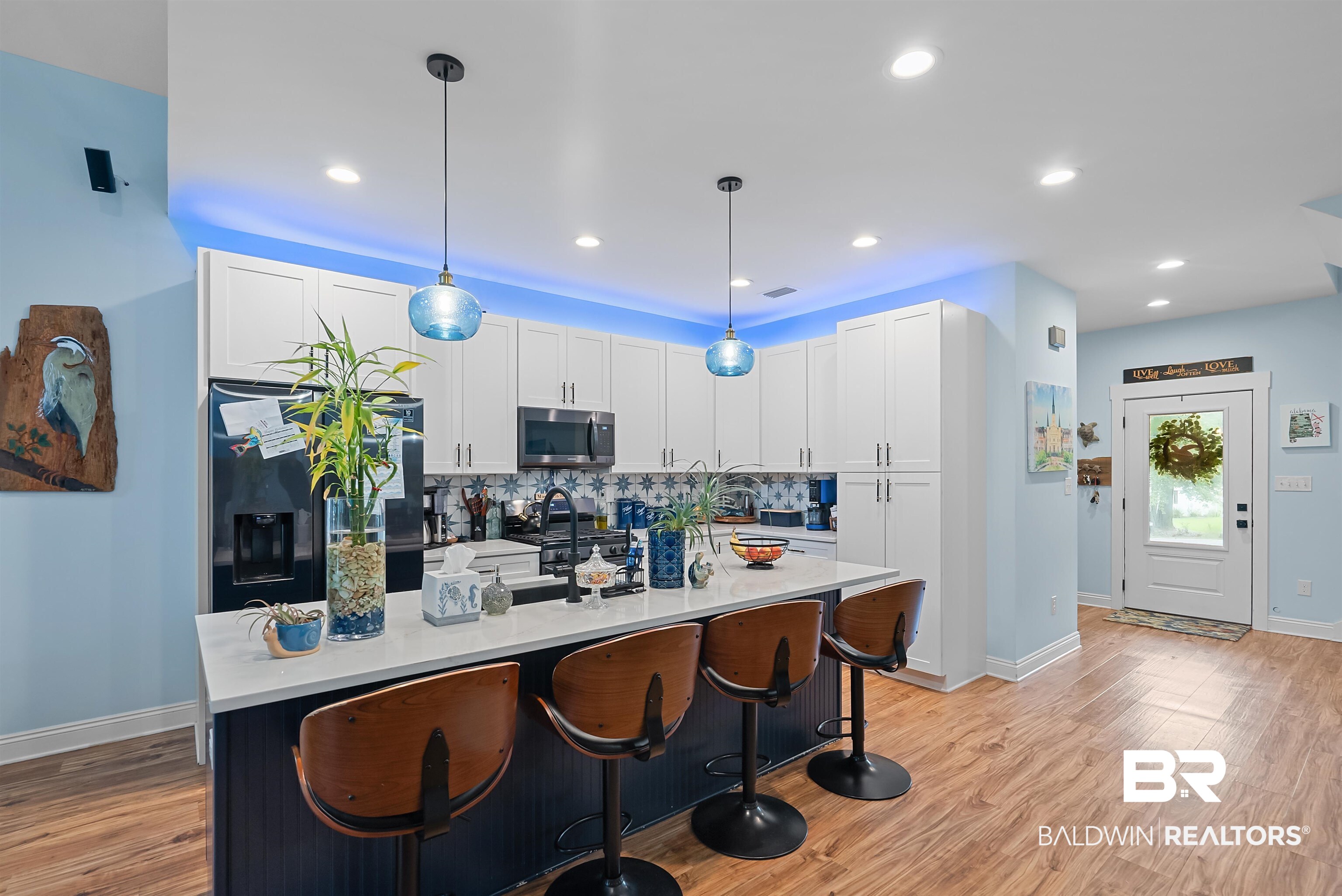 7266 Franklin Road Foley, AL 36535 - Photo 13 of 64 Modern kitchen featuring white cabinetry, a dark island with seating, pendant lighting, and wood-finish flooring