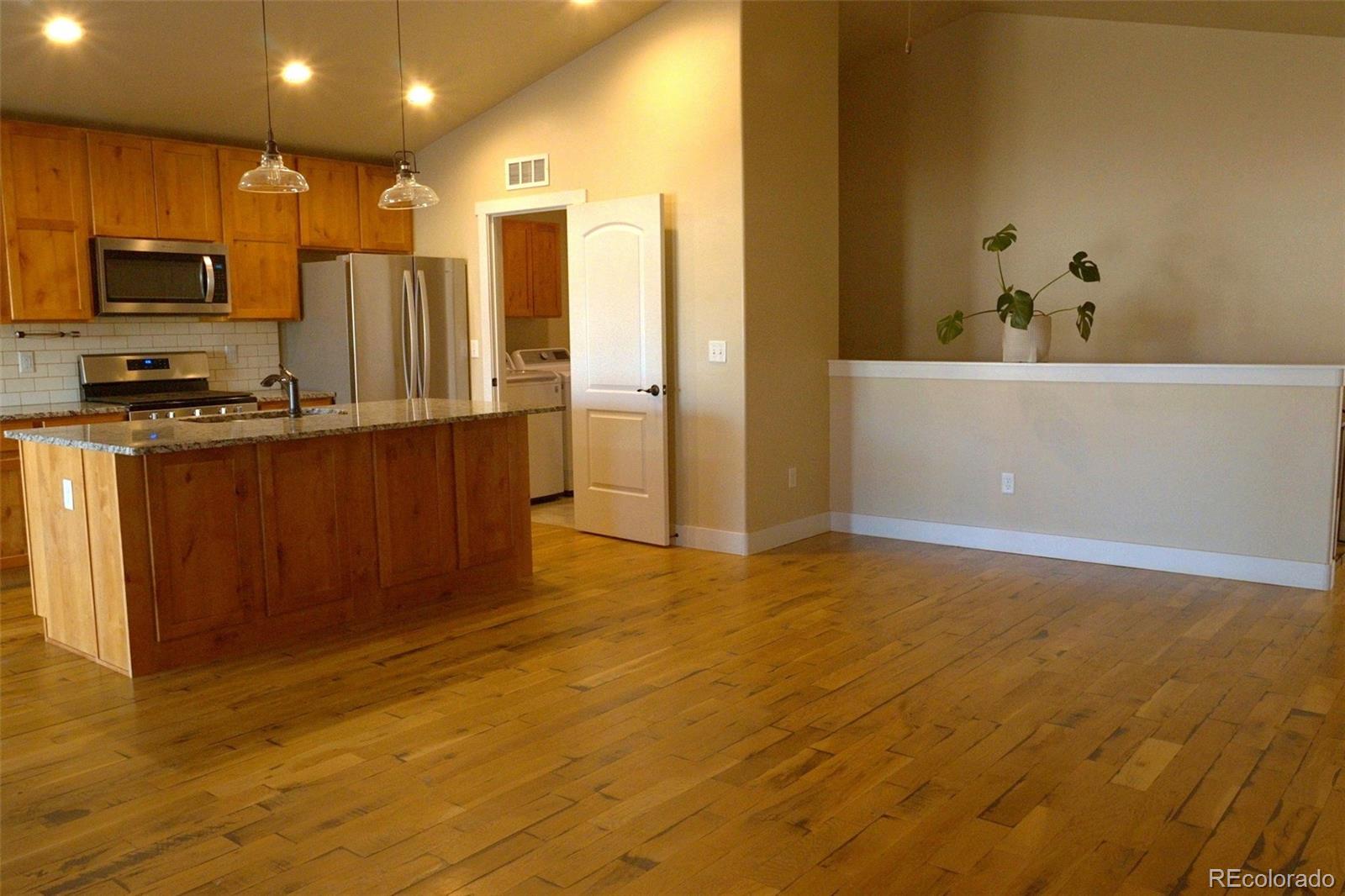 1113 Bison Way Wiggins, CO 80654 - Photo 4 of 20 a kitchen with stainless steel appliances a refrigerator and a stove top oven
