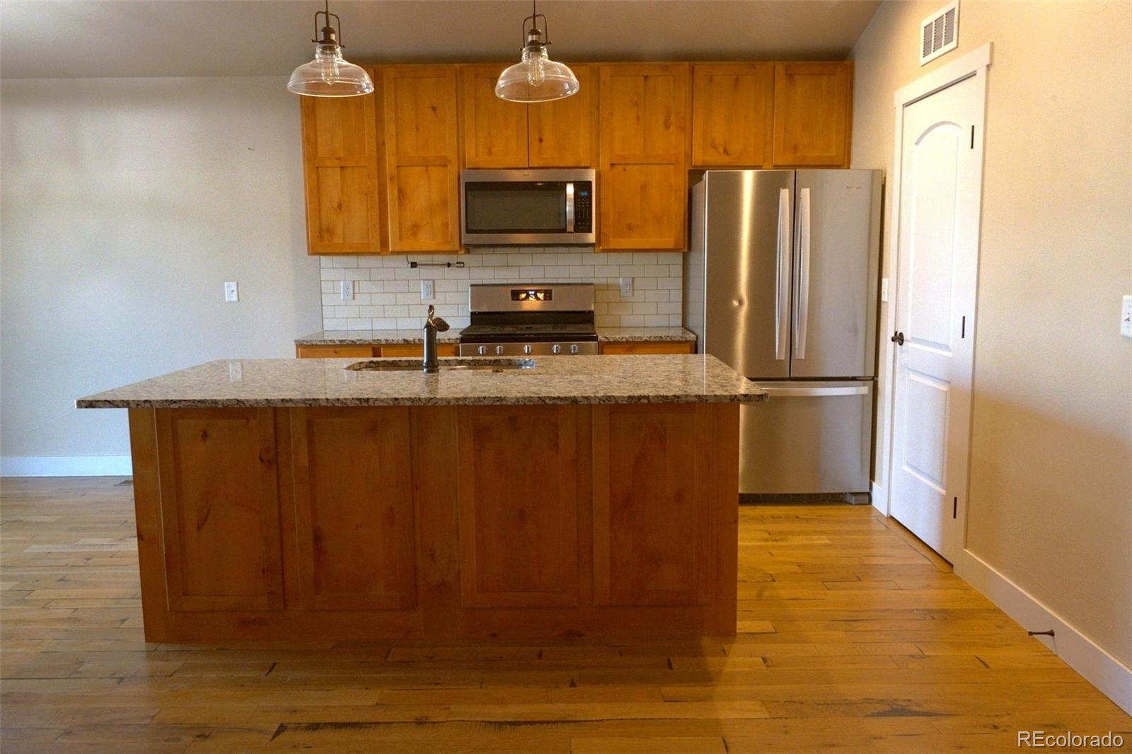 1113 Bison Way Wiggins, CO 80654 - Photo 8 of 20 a kitchen with stainless steel appliances granite countertop a refrigerator a stove top oven and a sink